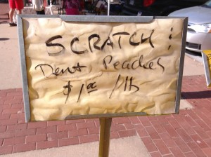 Sign advertising scratched and dented peaches for $1 per pound