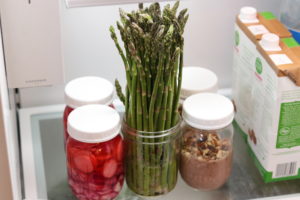 Mason jars being used to store asparagus, pickled veggies and pudding